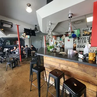 a bar with stools and people sitting at tables