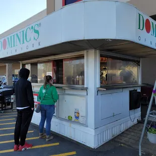 a man and a woman standing in front of a donut shop