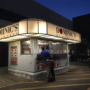 a man and a woman standing in front of a donut shop