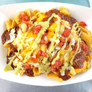 Frito Pie: Fritos, chili, melted cheese, chopped onions, chopped tomatoes, and jalapeño sauce