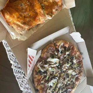 two pizzas in boxes on a table