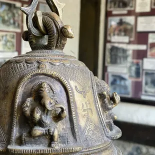 a close up of a bell with a statue on top