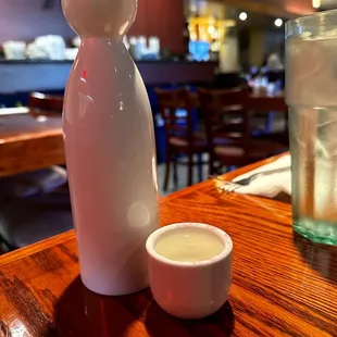 a white vase and a cup on a wooden table