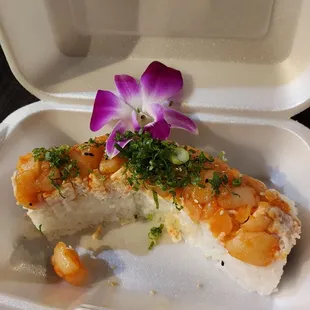 a piece of sushi in a styrofoam container