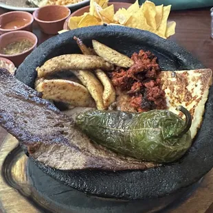 Molcajete - Carne asada, chorizo, grilled chicken, onions, and jalapeño. It's served with a rice &amp; beans.