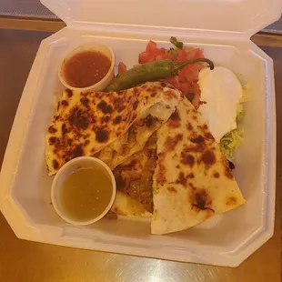 This is a chicken quesadilla with pico de gallo sour cream and red &amp; green salsa.