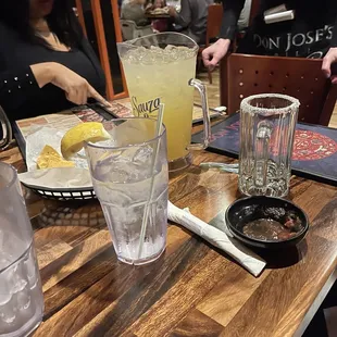 a wooden table with drinks and plates of food