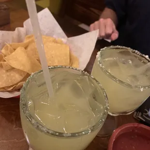 two margaritas and chips on a table