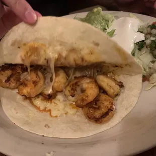 a plate of food with shrimp tacos and a salad
