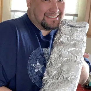 a man in a kitchen holding a foil wrap