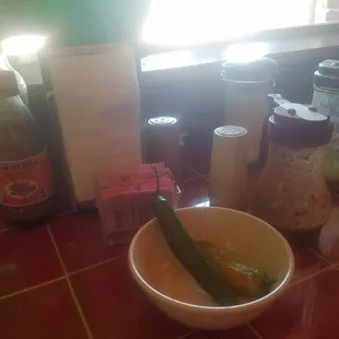 Two random serrano peppers and half filled bottles of salsa at each table