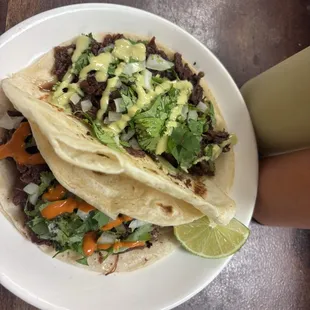 Barbacoa tacos on flour tortillas with red and green salsa