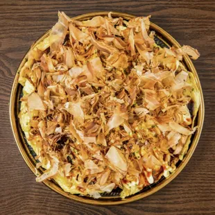 Yakisoba under a sheet of scrambled egg, bonito 
 and nori flakes.