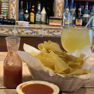 a bowl of chips and a bottle of salsa