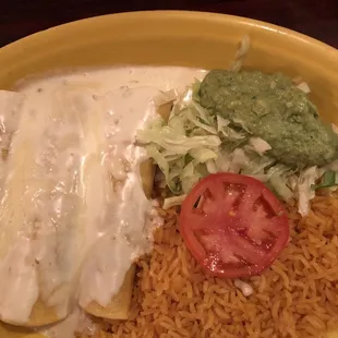 Three chicken enchiladas with cheese sauce.