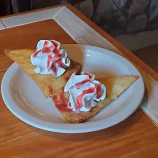 Complementary dessert, fried chips with whipped cream and raspberry glaze
