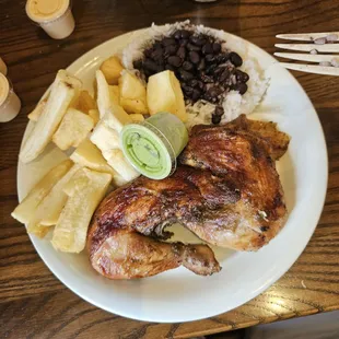 Half chicken dark with yucca, rice and beans.