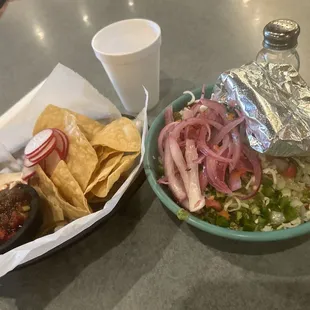 Burrito bowl with pickled onions from the salsa bar and corn tortillas on the side.