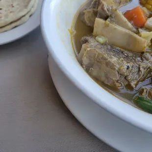 a bowl of stew and a plate of tortillas