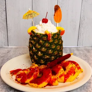 a pineapple topped with whipped cream and fruit