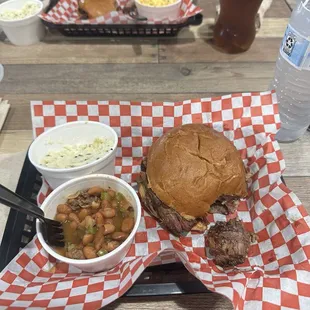 Brisket sandwich with a side of chili beans and potato salad