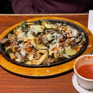 a pizza and a cup of sauce