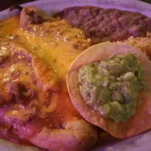 Chile Rellenos dinner served with a side of guacamole, beans, rice, and tortillas.