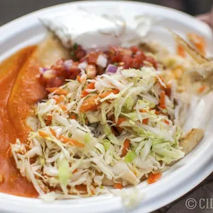 A delicious cheese pupusa with the works (sauce, slaw, sour cream, and pico de gallo).