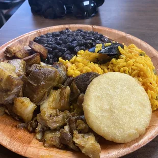 Seafood Paella with a side of black beans, pork bites, and arepa (the round item on plate)