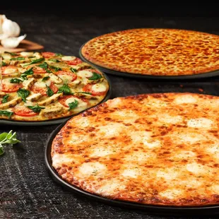 three different pizzas on a table