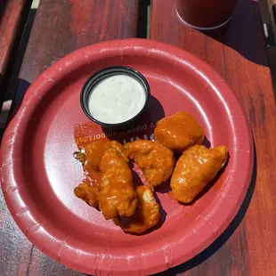 a plate of chicken wings and a cup of ranch dressing
