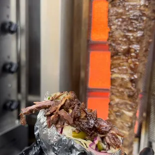 the meat being cooked on a skewer
