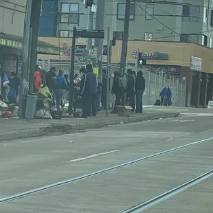 a group of people waiting on the side of the road