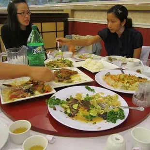 a group of people sitting at a table with plates of food