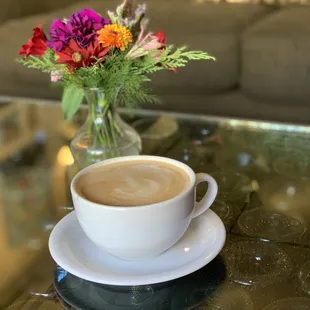 a cup of coffee and a vase of flowers