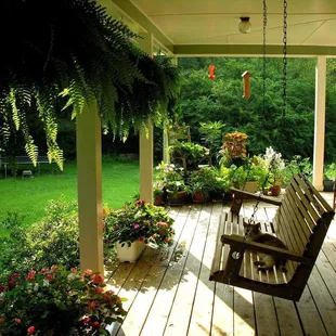 a porch with a bench and potted plants