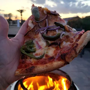 a hand holding a slice of pizza