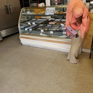 a woman standing in front of a display of donuts