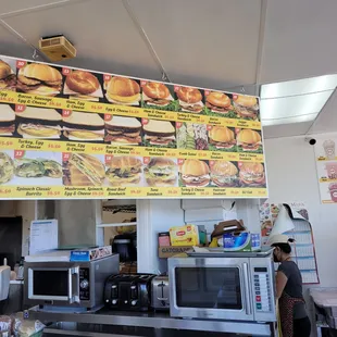 a woman standing in front of a menu board