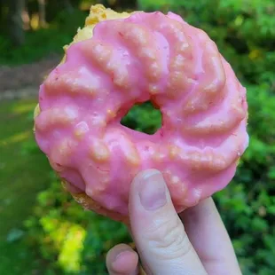 a hand holding a pink donut