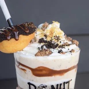 a hand holding a donut milkshake