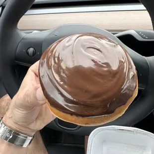 a man holding a chocolate frosted donut