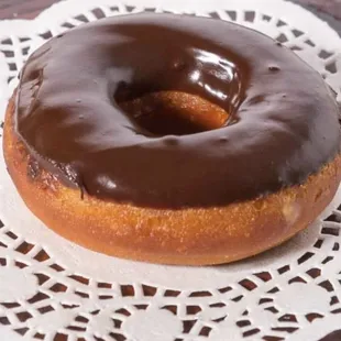 a chocolate frosted donut on a doily