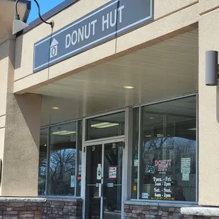 a donut shopfront with a car parked in front of it