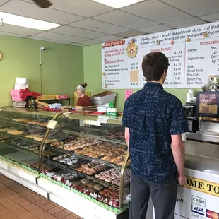 two men standing in front of a display of donuts