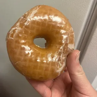 a hand holding a glazed donut