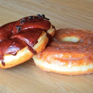 two chocolate covered donuts on a wooden table