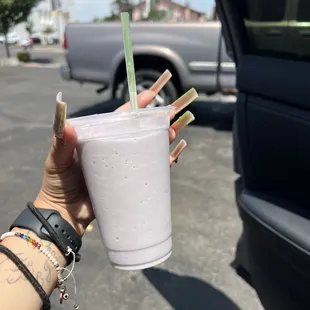a person holding a drink in a parking lot