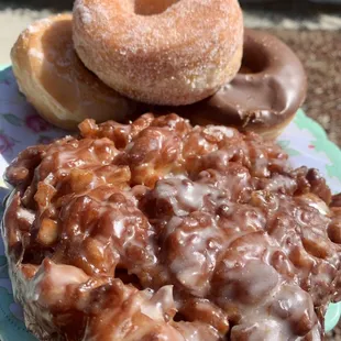 Glazed, sugar, chocolate donuts in the back and Apple fritter in the front