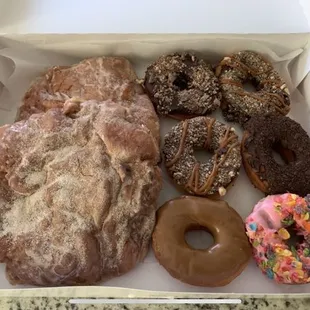 Two apple fritters, a KitKat donut, two snickers donuts, a grasshopper (mint and chocolate) a maple and a fruit loop donut.